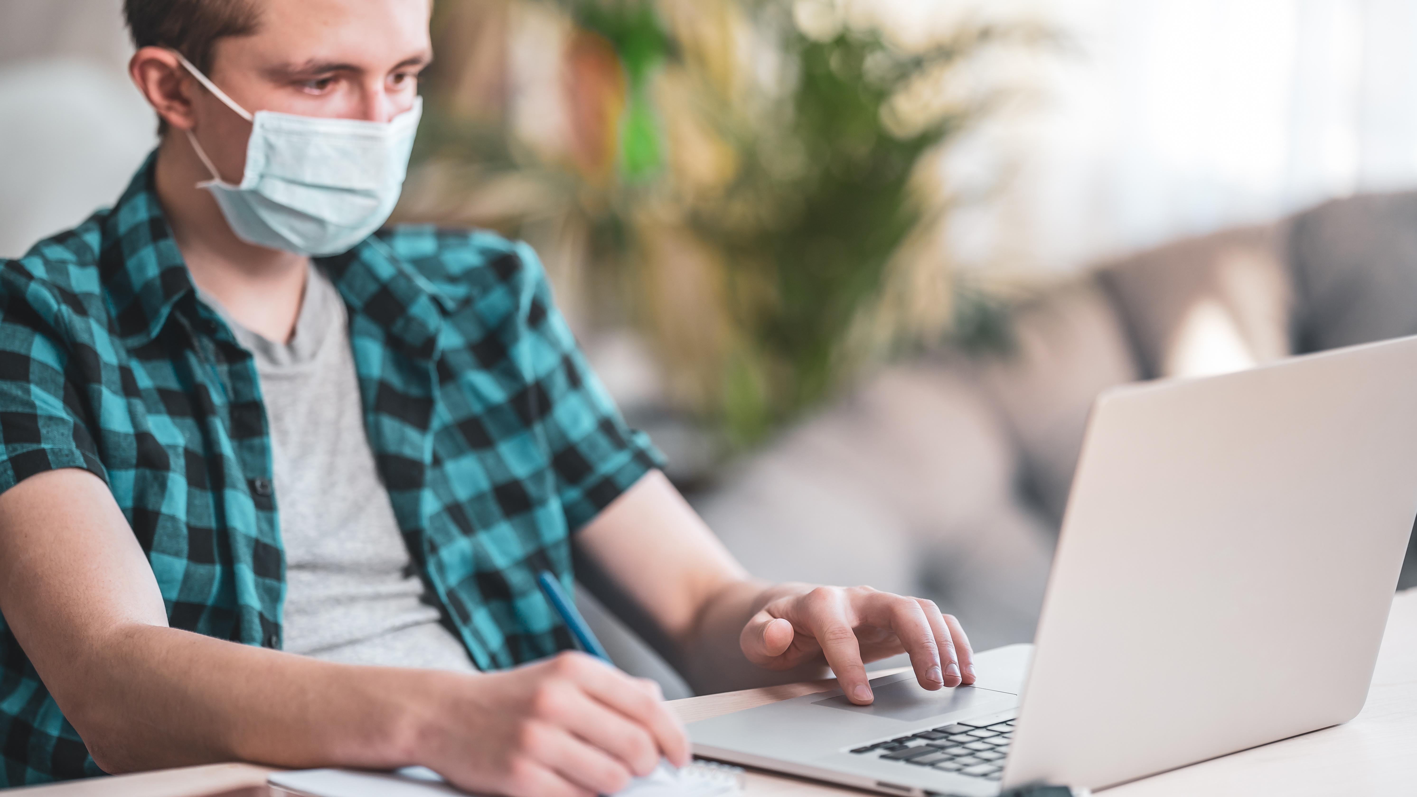 active teenager in mask and headphones with laptop during coronavirus quarantine